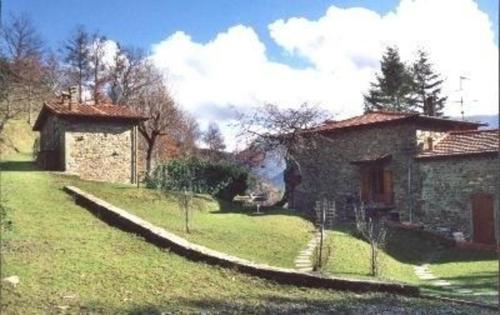 a stone house with a grassy yard next to a building at Appartement in Bibbiena mit Grill, gemeinsamem Pool und Garten in Bibbiena