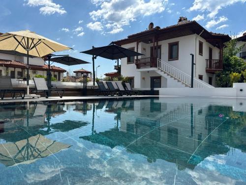 a pool with chairs and umbrellas in front of a house at Tomsan Villas Akyaka in Akyaka