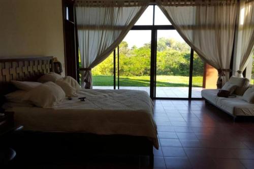 een slaapkamer met een bed en een groot raam bij Casona los Bambú in San José