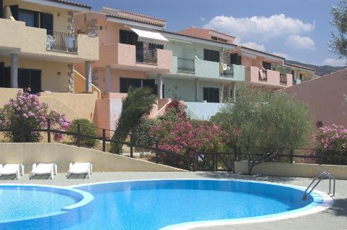 a swimming pool with two chairs and some buildings at Borgo del Tennis - Sa Ventana 2 in Badesi