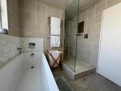 La salle de bains est pourvue d'une baignoire et d'une douche en verre. dans l'établissement Cozy family beachfront house., à Langstrand
