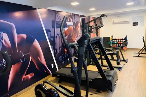 um ginásio com máquinas e um mural de parede em Aptos super confortáveis no Gold Flat by Apartamentos Jampa em João Pessoa