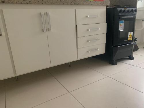 una cucina con armadietti bianchi e stufa nera di Otimo apartamento de 02 quartos a Cabo Frio