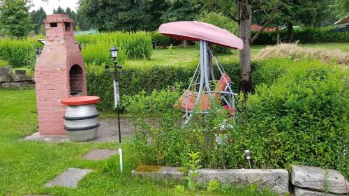 um jardim com uma casa de pássaros e um guarda-chuva em Ferienzimmer im Thüringer Wald nahe dem Rennsteig em Siegmundsburg