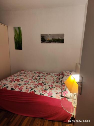 a bedroom with a bed with a flowered bedspread and a lamp at Altstadt Zimmer in Düsseldorf