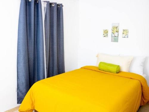 a yellow bed in a room with blue curtains at Cozy Two Bedroom Apartment Near The U.S. Embassy in Antiguo Cuscatlán