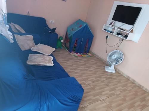 Casa amanhecer 2 في إتابيسيريكا دا سيرا: غرفة معيشة مع أريكة زرقاء ومروحة