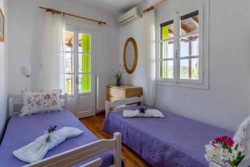 a bedroom with two beds and two windows at Avgeri Villa in Skopelos Town