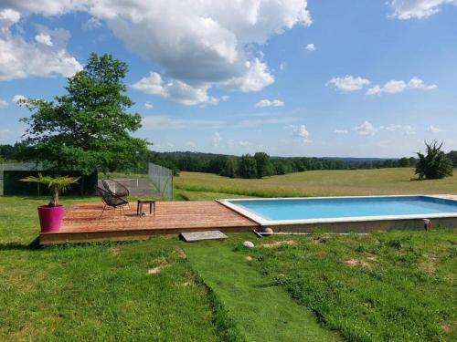 une terrasse en bois avec une piscine dans un champ dans l'établissement Maison de campagne Dordogne, à Les Lèches