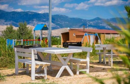 a picnic table and benches with a view of the mountains at Izzi Mobile Home - Terra Park SpiritoS in Kolan