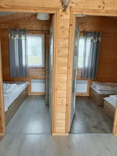 a large room with two beds and two windows at Domki nad morzem Park Jesionów in Pleśna