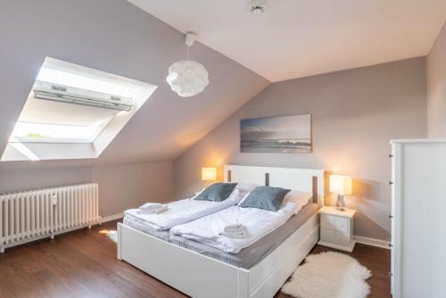 a bedroom with a white bed and two skylights at Ferienwohnung Beachside in Strande