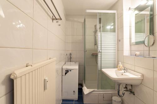 a white bathroom with a sink and a shower at Ferienwohnung Beachside in Strande