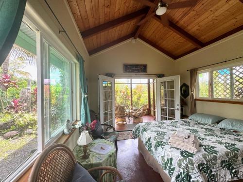 a bedroom with a bed and some windows at Tropical Zen Bungalow in Pahoa