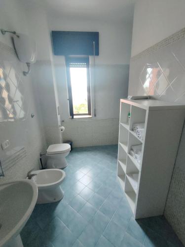 een badkamer met 2 toiletten, 2 wastafels en een raam bij Affittacamere sunset in Castel Volturno
