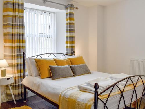 a bedroom with a bed with yellow pillows and a window at Little Bere in Lifton