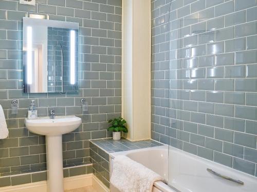 a blue tiled bathroom with a sink and a bath tub at Little Bere in Lifton