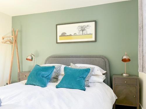 a bedroom with a white bed with blue pillows at Honey Bee Cottage in Calbourne