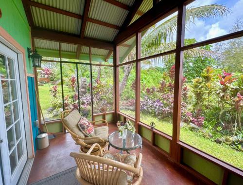 Pahoa的住宿－Tropical Zen Bungalow，门廊上设有椅子和玻璃桌