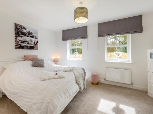 a bedroom with a large white bed with two windows at Haras House in Tiverton