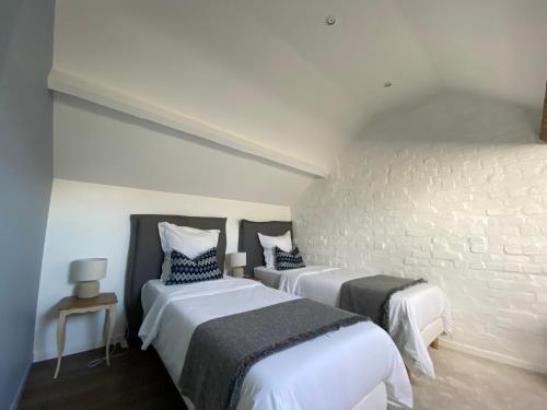 a bedroom with two beds and a brick wall at Cottage de charme proche de Paris in Fontenay-en-Parisis