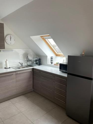 Il comprend une cuisine équipée d'un réfrigérateur et d'une horloge murale. dans l'établissement Ducey Appart'Hôtel - Les Rivières, à Ducey