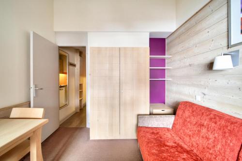 Cette chambre dispose d'un canapé rouge et d'un mur en bois. dans l'établissement Résidence Plagne Lauze - maeva Home - Studio 2 personnes - Confort MAE-0914, à Mâcot La Plagne