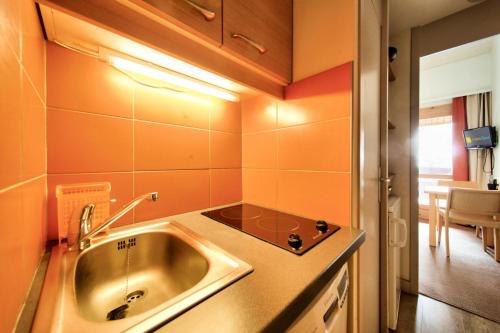 une petite cuisine avec un évier et une table dans l'établissement Résidence Plagne Lauze - maeva Home - Studio 2 personnes - Confort MAE-0914, à Mâcot La Plagne