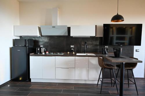 a kitchen with white cabinets and a black refrigerator at Suite 115 - Luxury Rooms in Capoterra