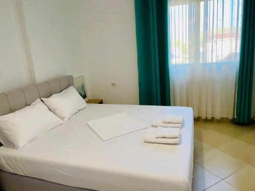 ein Schlafzimmer mit einem weißen Bett und Handtüchern darauf in der Unterkunft Divjaka Apartments 3 - City Center in Divjaka
