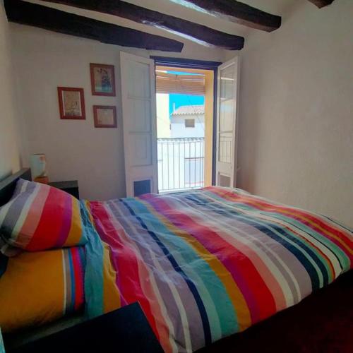 Cama colorida en habitación con ventana en Traditional Spanish Town House, en Móra d'Ebre