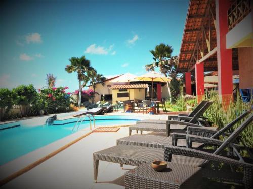 een zwembad met terrasstoelen en een huis bij Pousada Villa Flamboyant in Beberibe