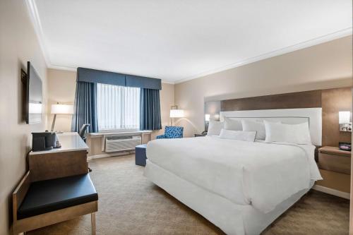 a large bedroom with a large white bed and a window at Best Western Plus Columbia River Hotel in Trail