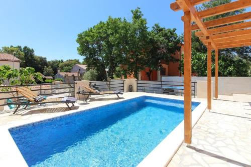 a swimming pool with a wooden pergola next to a house at Ferienhaus mit Privatpool für 6 Personen ca 85 qm in Barbariga, Istrien Istrische Riviera in Barbariga