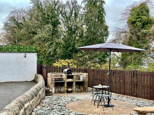 a patio with a table and an umbrella at Gleddoch Coach House in Langbank