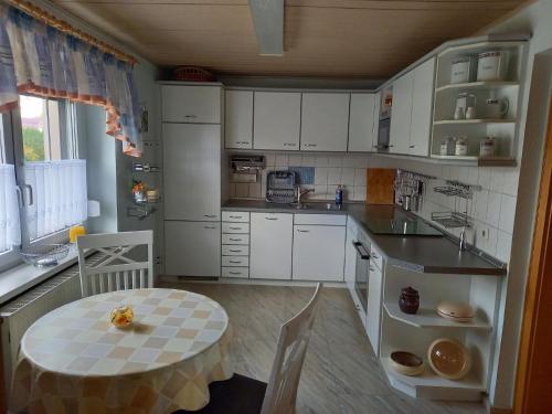 cocina con armarios blancos, mesa, mesa y mesa en Appartement in Zescha mit Terrasse und Garten en Neschwitz