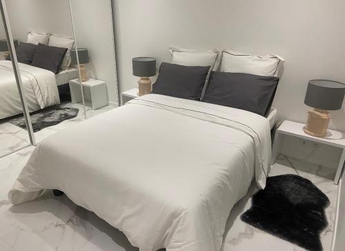 - une chambre avec un grand lit blanc et des miroirs dans l'établissement Appartement 3 pièces rénové, à Beausoleil