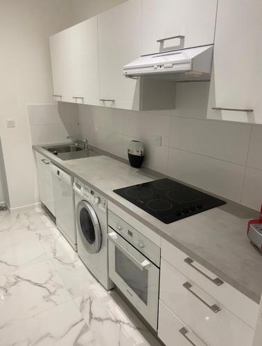 une cuisine blanche avec une cuisinière et un évier dans l'établissement Appartement 3 pièces rénové, à Beausoleil