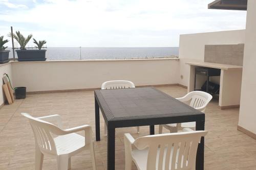 een zwarte tafel en witte stoelen op een balkon met uitzicht op de oceaan bij Il terrazzo sul porto in Sciacca