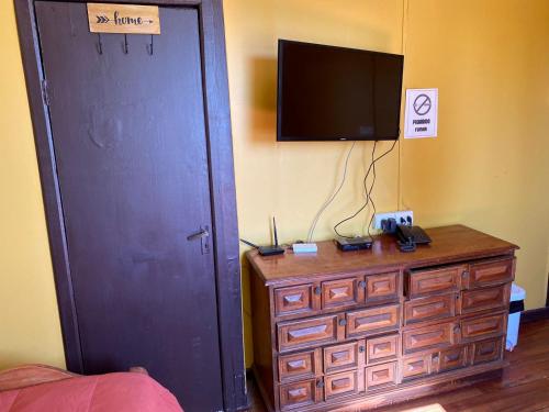 モリーナにあるHostal Radal Molinaのベッドルーム1室(テレビ付)、木製ドレッサー1台(ドレッサー付)