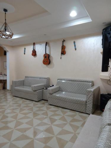 uma sala de estar com dois sofás e guitarras na parede em استراحة زمردة em Khasab