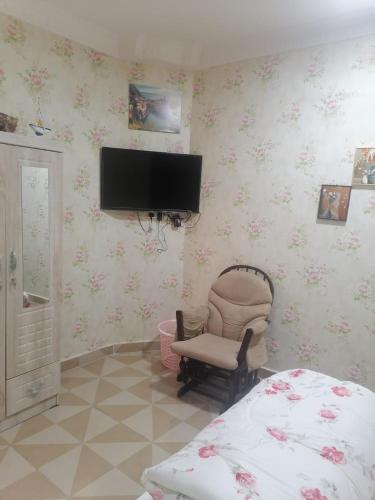 a bedroom with a chair and a tv on the wall at استراحة زمردة in Khasab