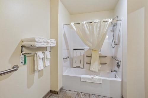 ein Bad mit einer Badewanne und einer Dusche mit Handtüchern in der Unterkunft Cobblestone Hotel & Suites - Rhinelander in Rhinelander