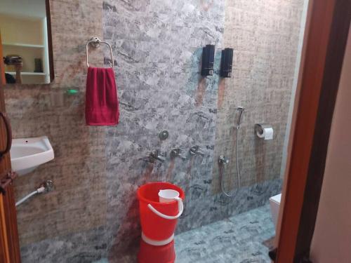 uma casa de banho com um chuveiro com um balde vermelho em Happy Camper Comfortable & Peaceful Place 1 RK 101 em Mysore