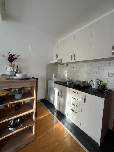 a kitchen with white cabinets and a wooden floor at Studio29 in Ruma