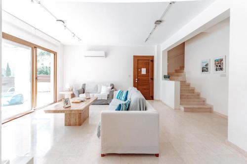 a white living room with a couch and a table at WealthyStays Sunset Villa, 3min walk to Sea in Paralimni