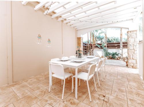a white dining room with a white table and chairs at WealthyStays Sunset Villa, 3min walk to Sea in Paralimni