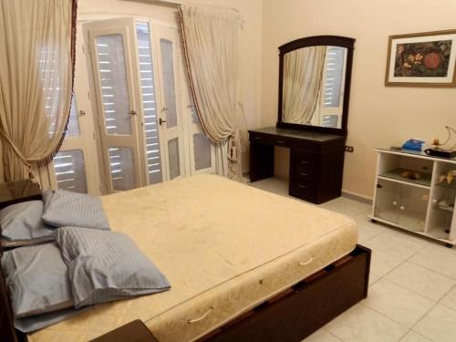 1 dormitorio con 1 cama grande y espejo en Marina 7 El alamein North Coast villa فيلا مارينا 7 العلميين الساحل الشمالى en El Alamein