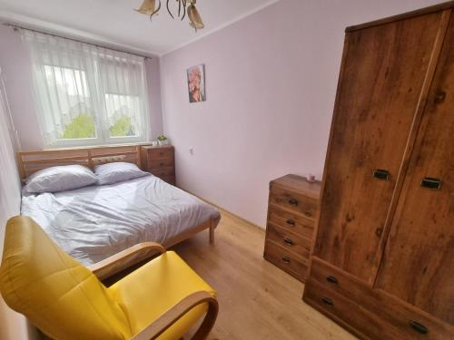 a bedroom with a bed and a yellow chair at Apartament 2-pokojowy Gdynia - Trójmiasto in Gdynia