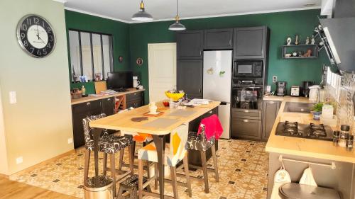 una cucina con pareti verdi e tavolo con sedie di Maison de famille a Benet